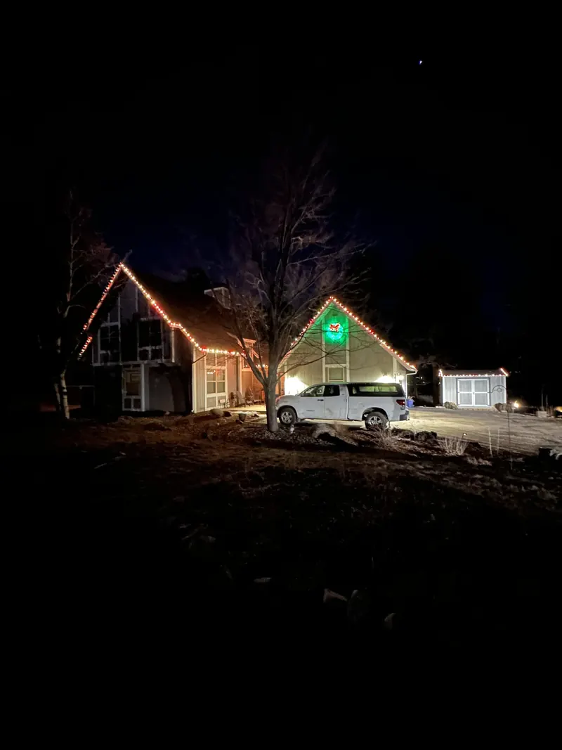 Gabled home with white lights and a lit green wreath