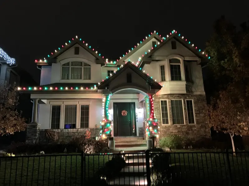 Two-story home with red, green and white lights and lit door columns