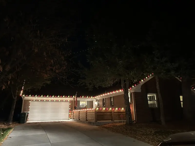 Ranch home and garage with red and white lights under trees