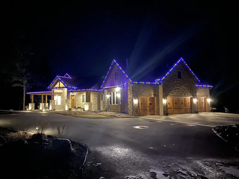 Stone ranch home with blue and white roofline lights