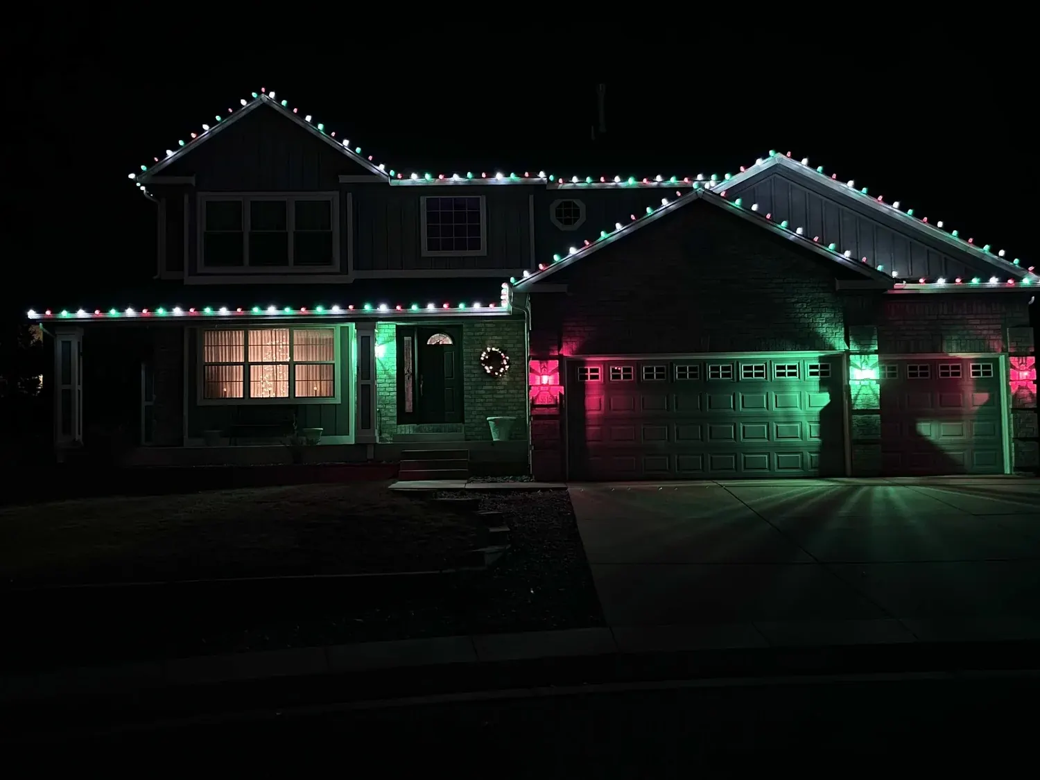 Two-story home with red, green and white lights along every roofline